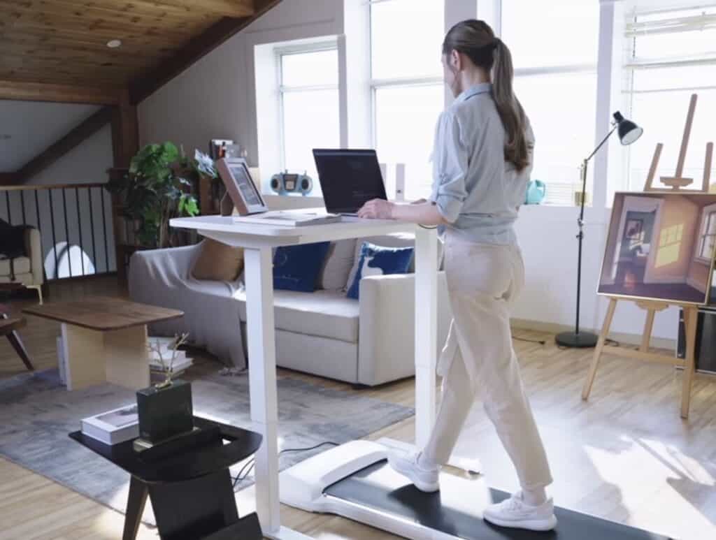 A woman using a standing desk in a living room.