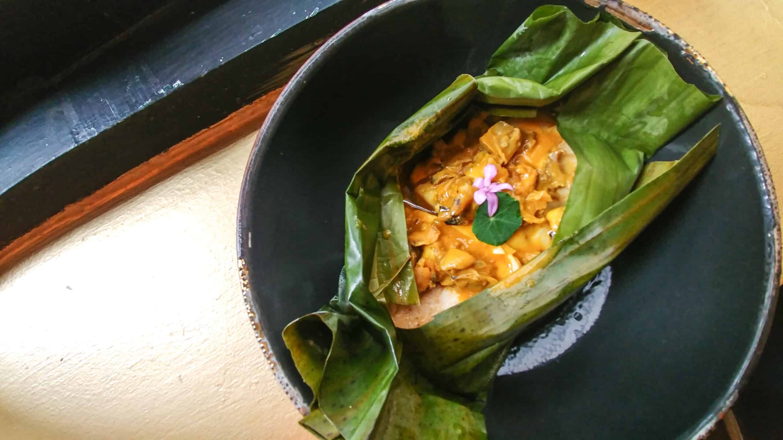 A bowl of food placed elegantly on top of a vibrant banana leaf, showcasing the culinary skills of one of the best restaurants in Bogota.