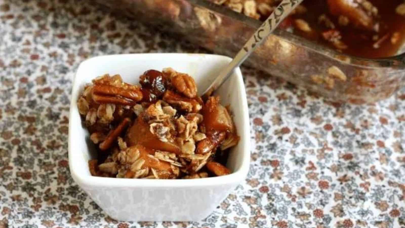 A bowl of crumble with oats and pecans with a spoon.