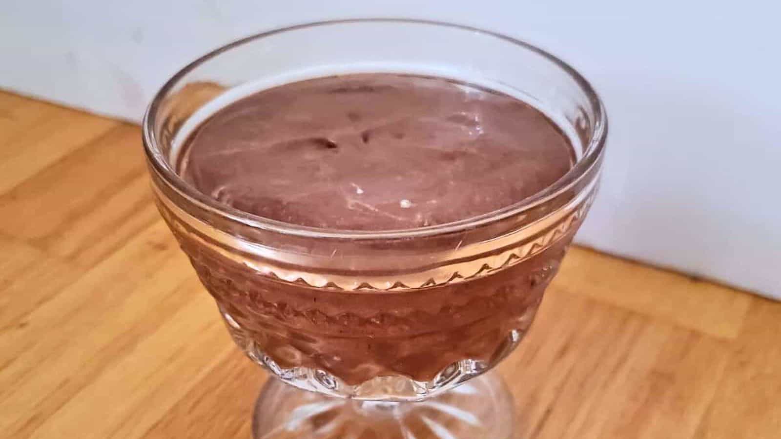 Image shows A glass of bourbon chocolate mousse sitting on a wooden table.