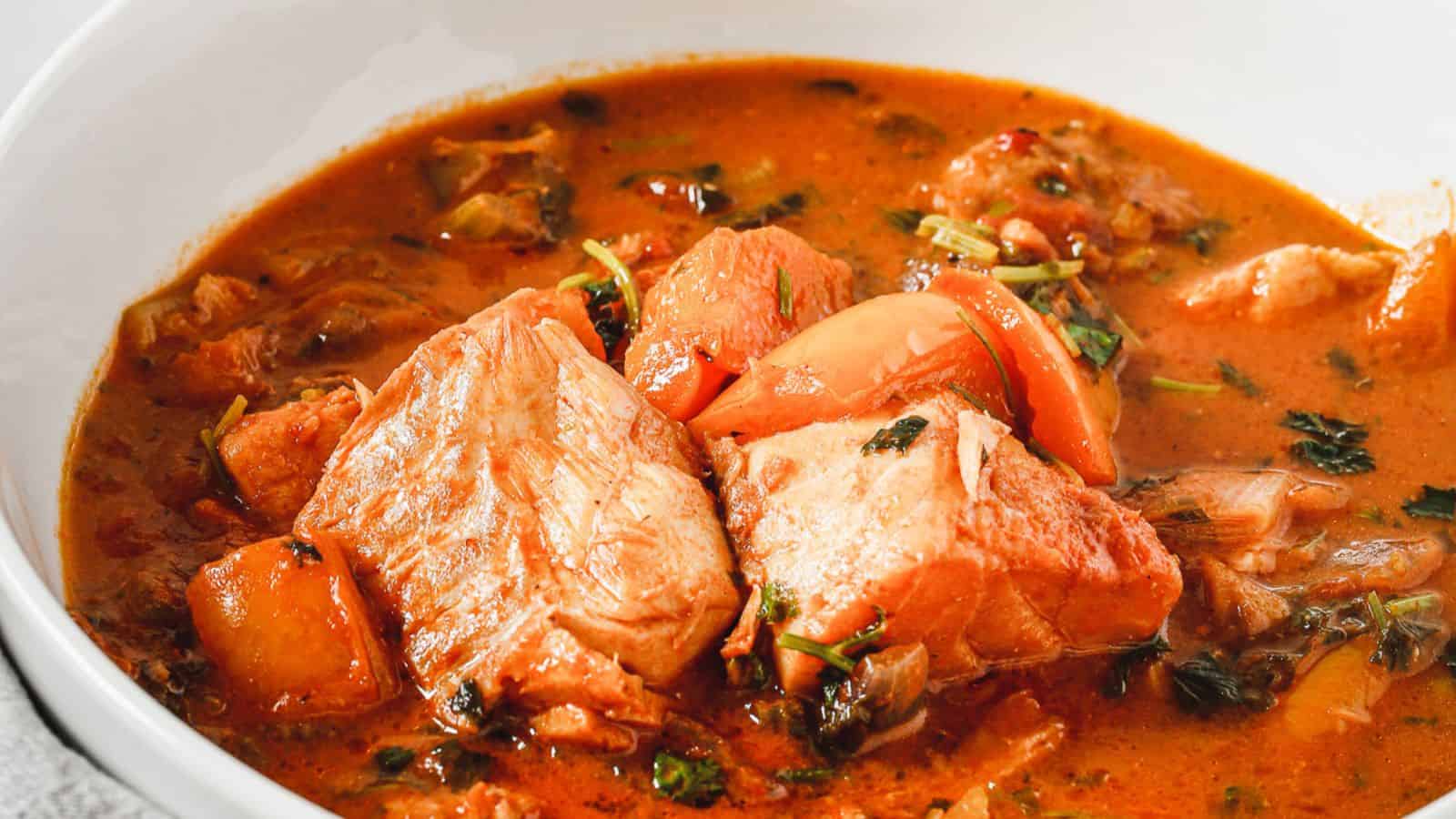A bowl of stew with fish in it.