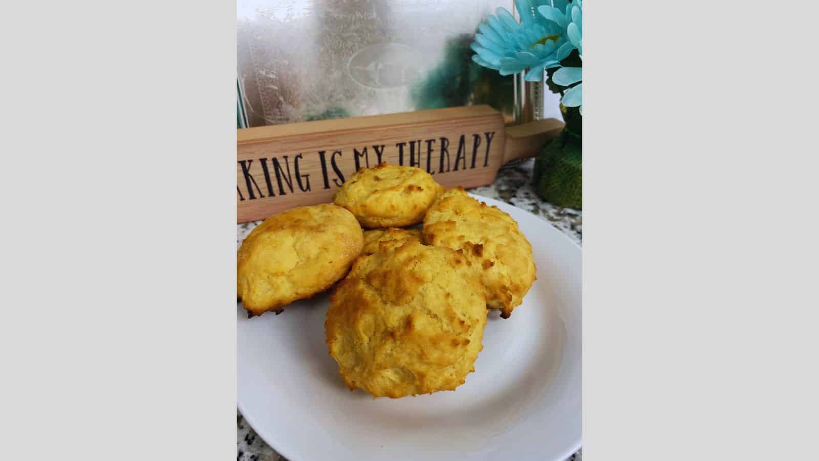 A plate of biscuits on a table with a sign.