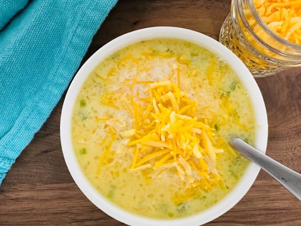 A bowl of soup with cheese and green peppers.