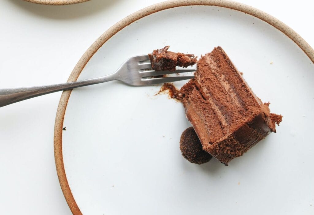 A slice of chocolate cake on a plate with a fork.