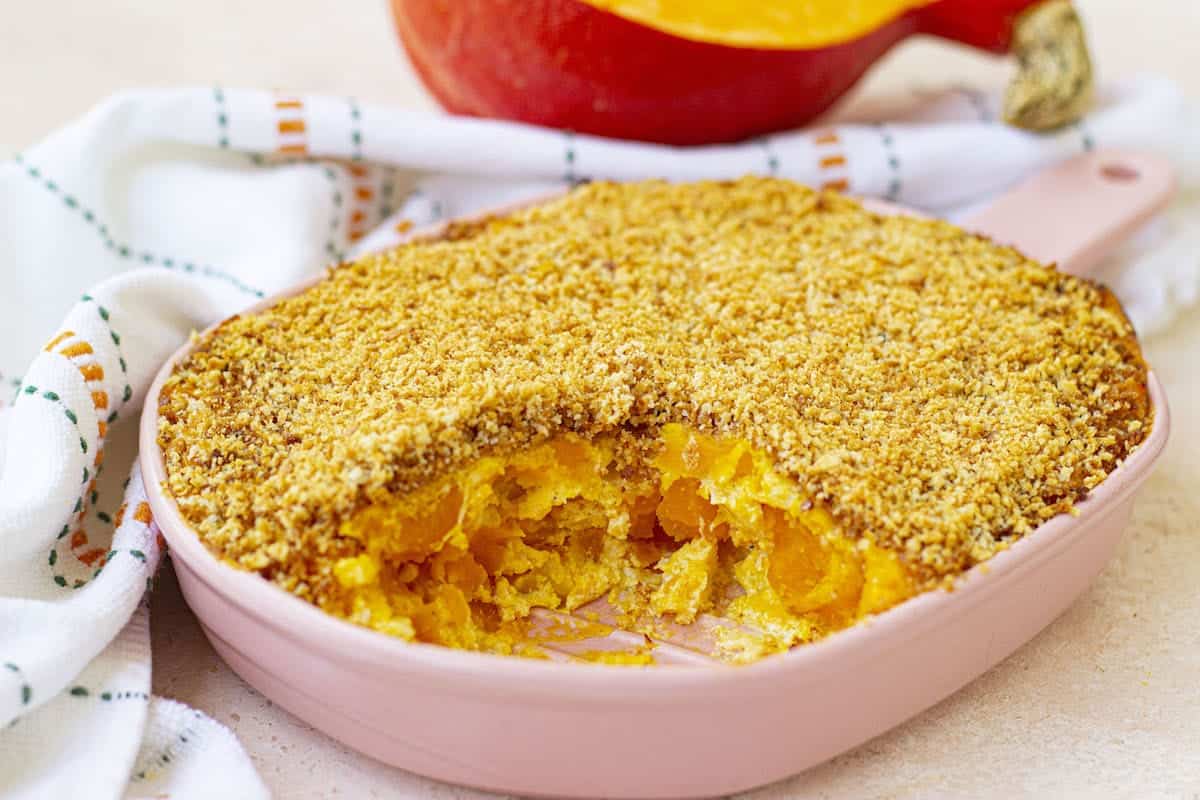 A pink dish with a squash casserole.