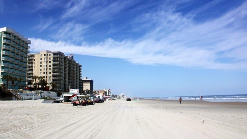 On a sunny day in Daytona, the beach is lined with cars and buildings, offering plenty of things to do.
