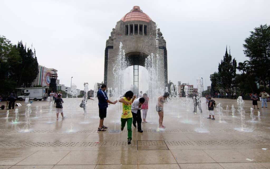 A group of people standing in front of a fountain during their Mexico City travel.