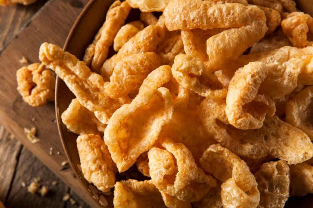 Pork rinds in a bowl on a wooden table.