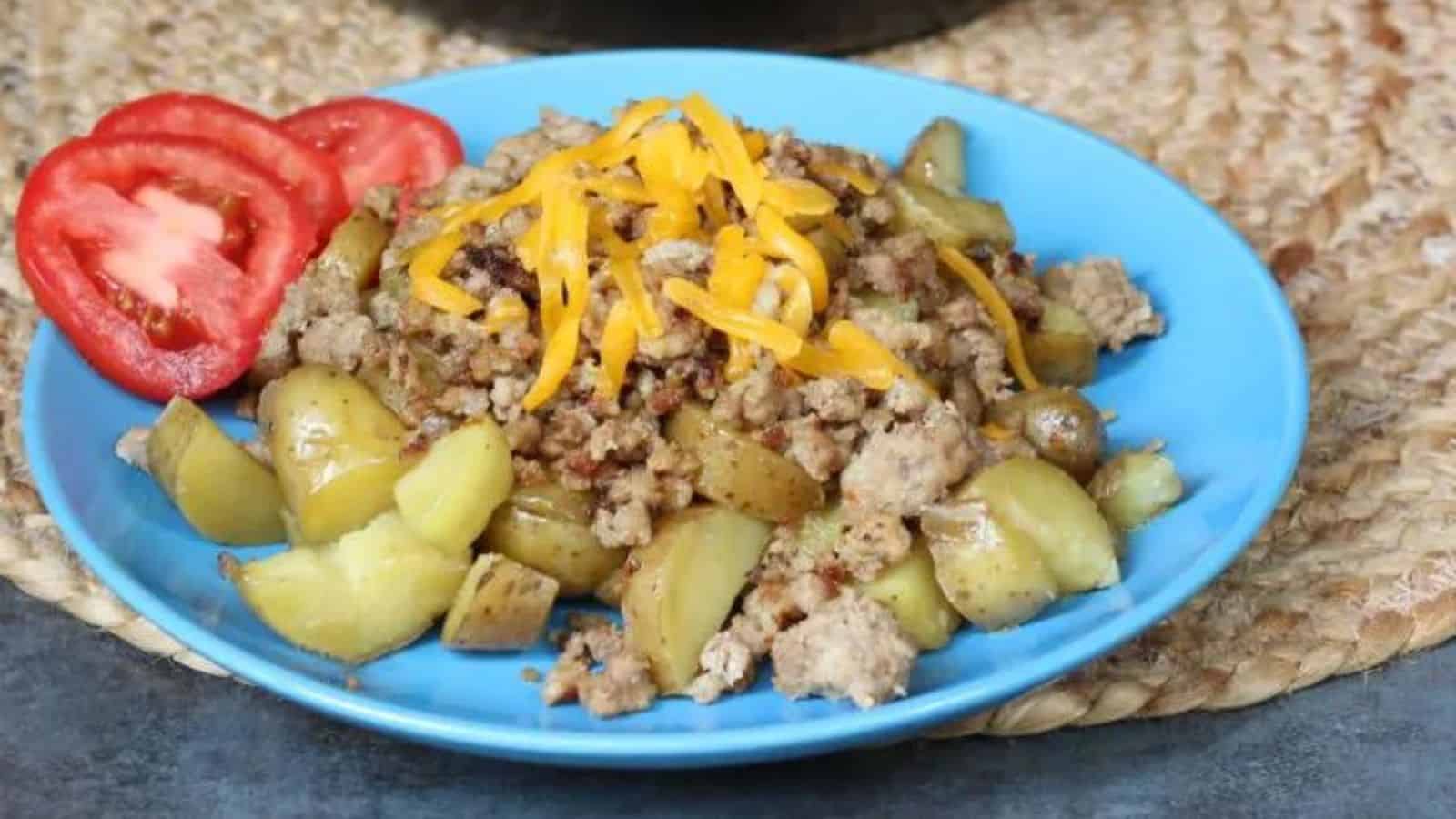 A blue plate with meat, potatoes and tomatoes.