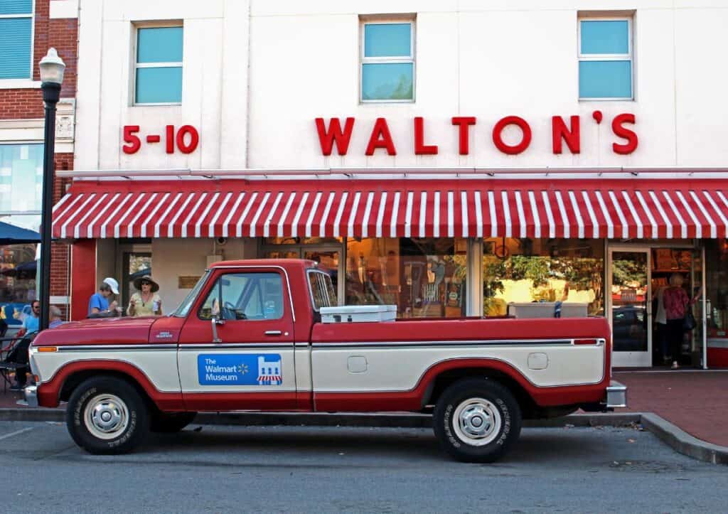 A red and white truck parked in front of a store.
