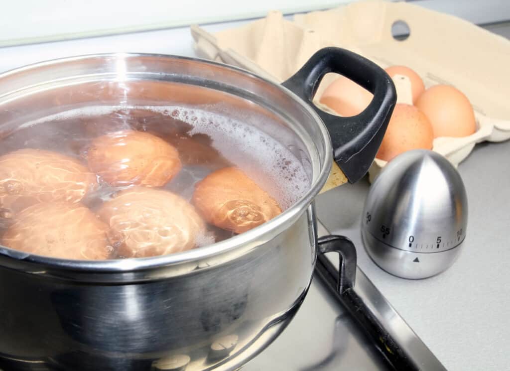A pot with eggs in it on a stove top.
