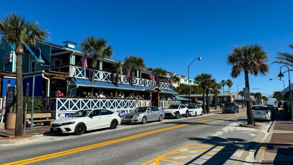 A street with cars parked in front of a restaurant, a popular attraction among things to do in New Smyrna Beach.