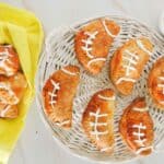 A basket of football shaped buffalo chicken pockets on a table.