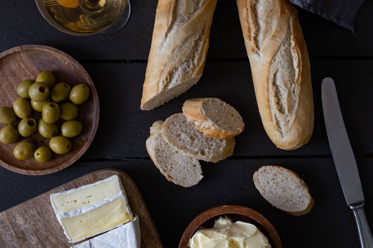 Bread, olives, and cheese on a wooden table.