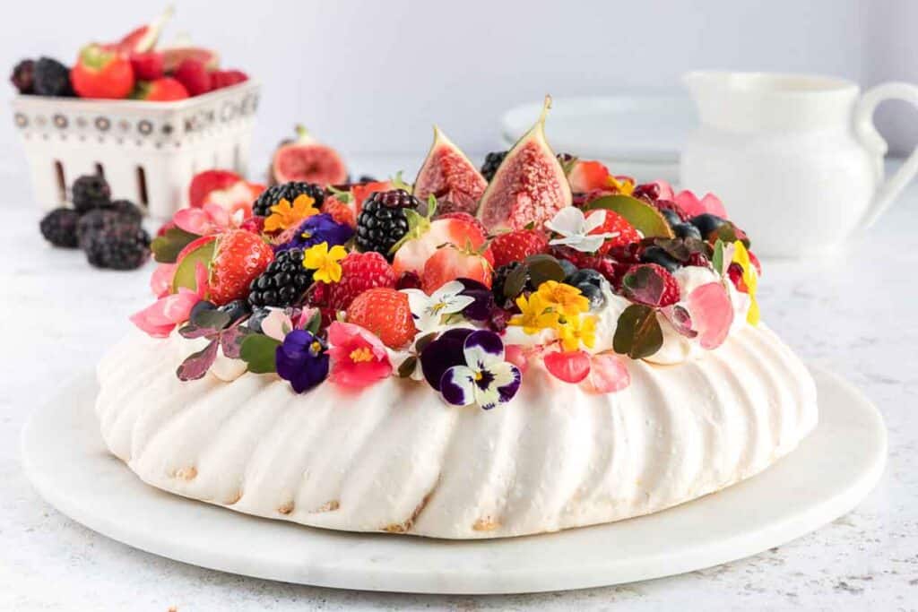 Meringue pavlova with figs and berries on a white plate.