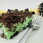 A slice of green oreo pie on a plate with a fork.