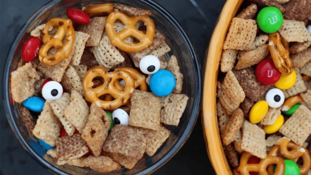 Two bowls of chex mix with eyes and candy.