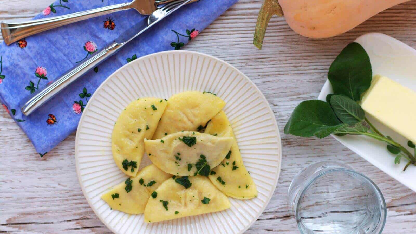 Homemade butternut squash ravioli in a brown butter sage sauce on a white plate.