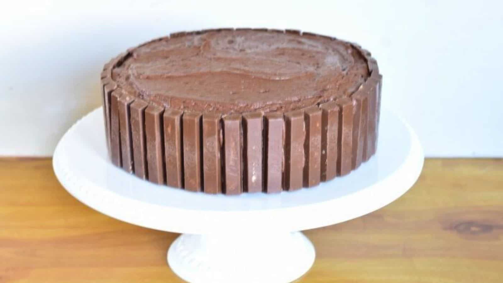 Image shows a Kit Kat cake on a white cake stand with a white background.