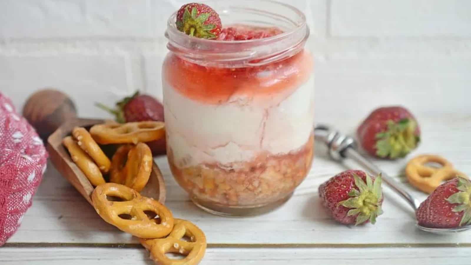 Jar of dessert with strawberries and pretzels.