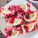 Lemon cranberry cheesecake bars on a white plate.