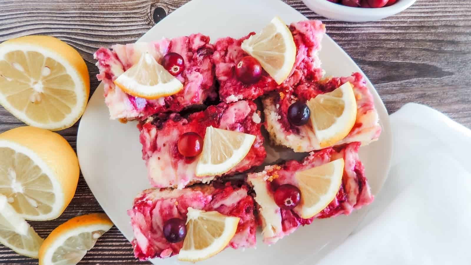 Lemon cranberry cheesecake bars on a white plate.