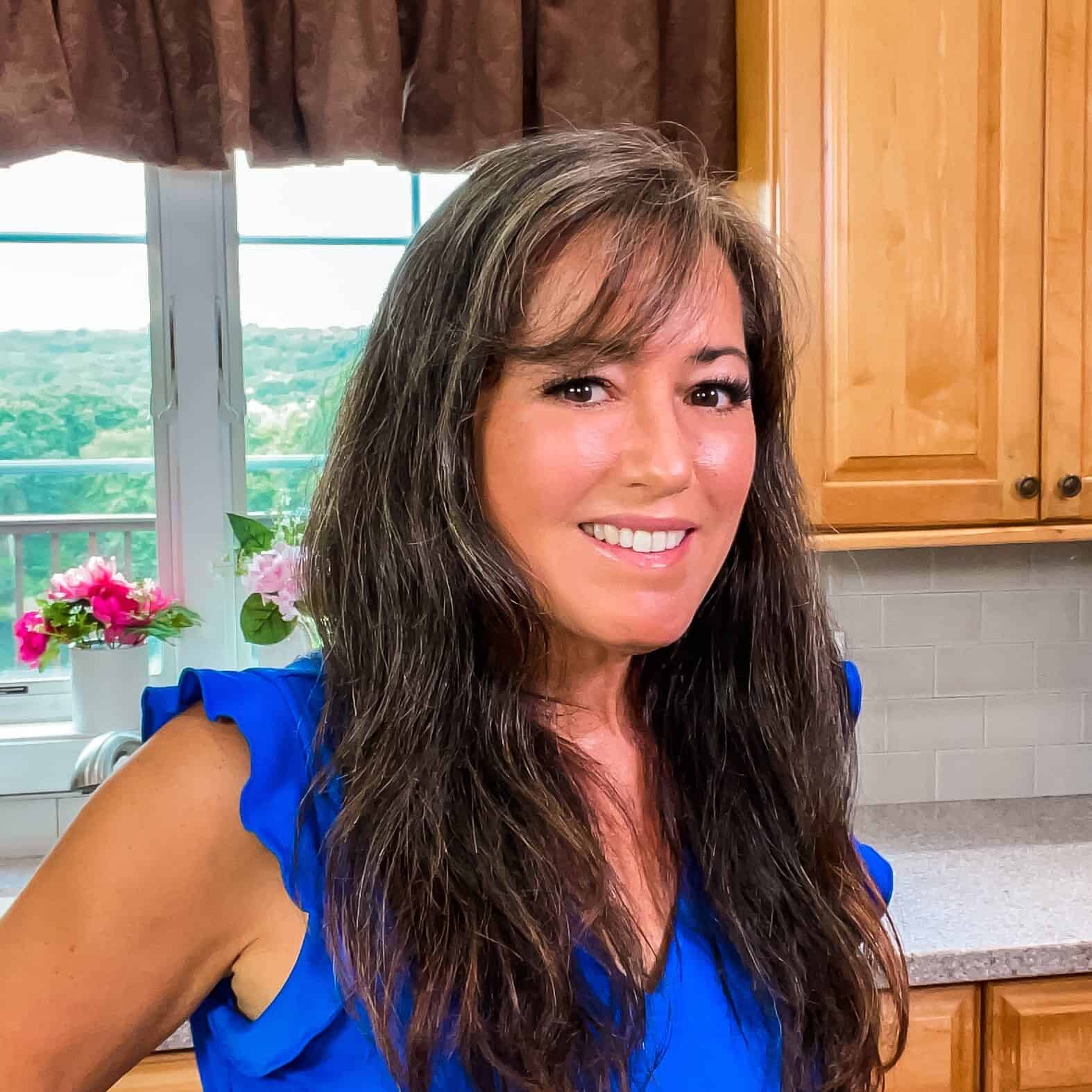 A woman in a blue dress standing in a kitchen.