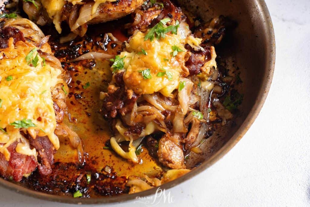 Chicken breasts in a skillet with onions and cheese.