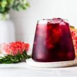 A glass of pomegranate juice with rosemary and pomegranate seeds.