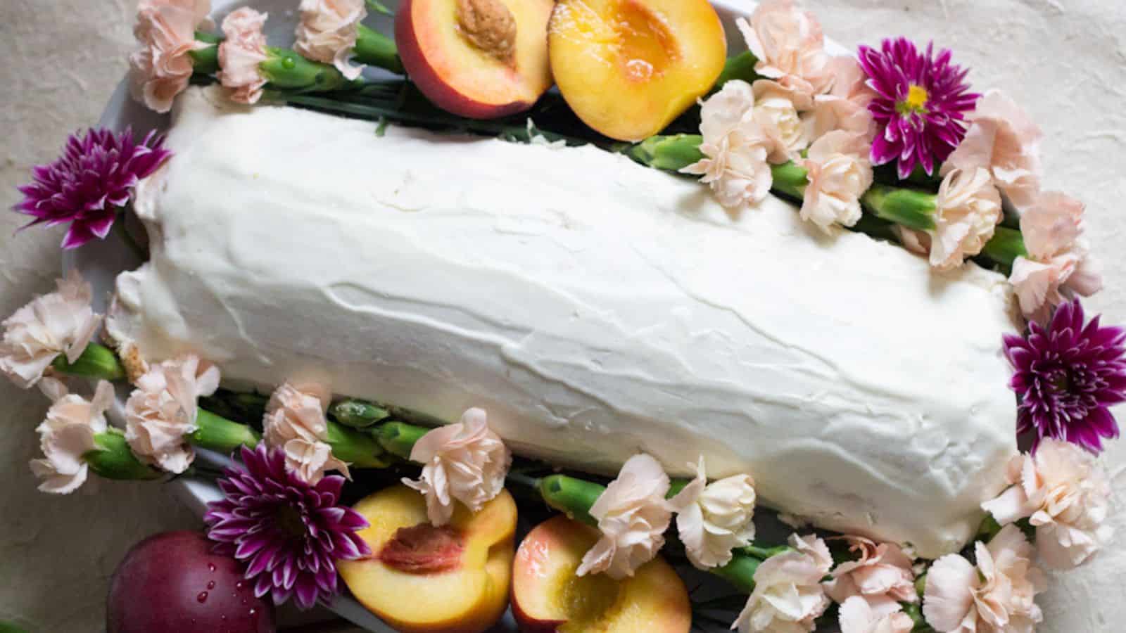A cake topped with peaches and flowers.