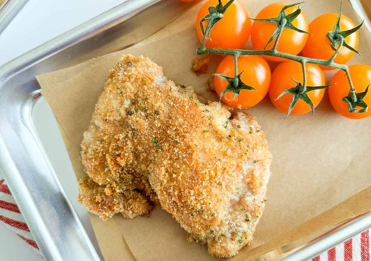 Oven fried chicken with cherry tomatoes.