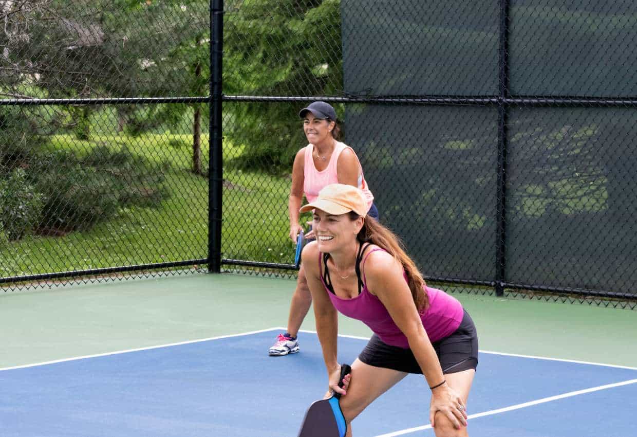 Two women on a pickleball court.