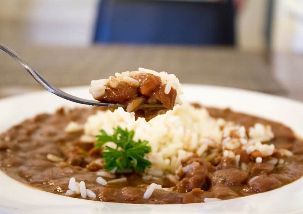 A flavorful plate of Mardi Gras food featuring a spoon full of beans and rice.