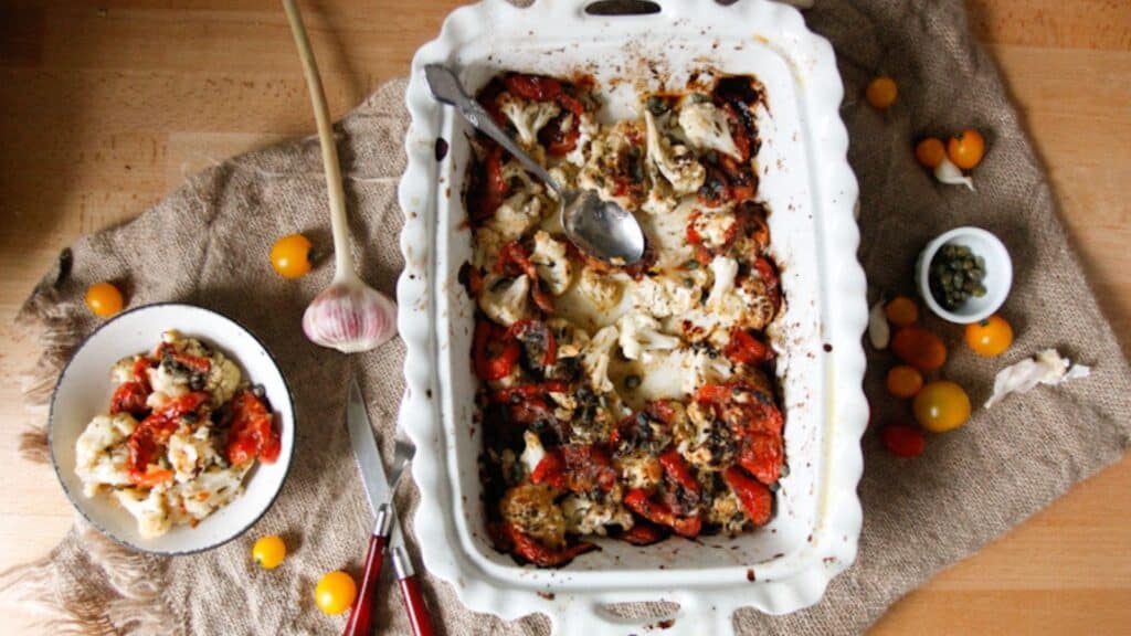 Cozy casserole dish featuring tomatoes and herbs on a table.