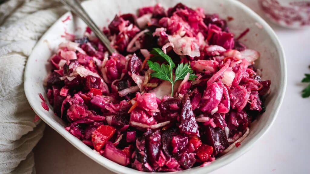 Red cabbage salad in a white bowl.