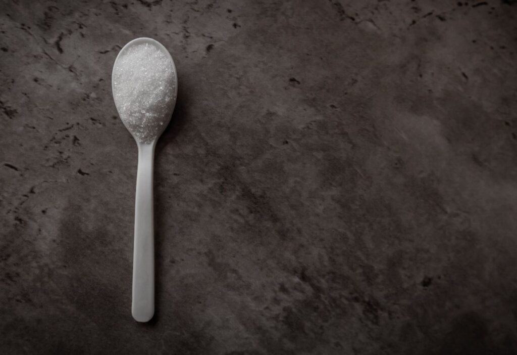 A spoon with sweeteners on a dark background.