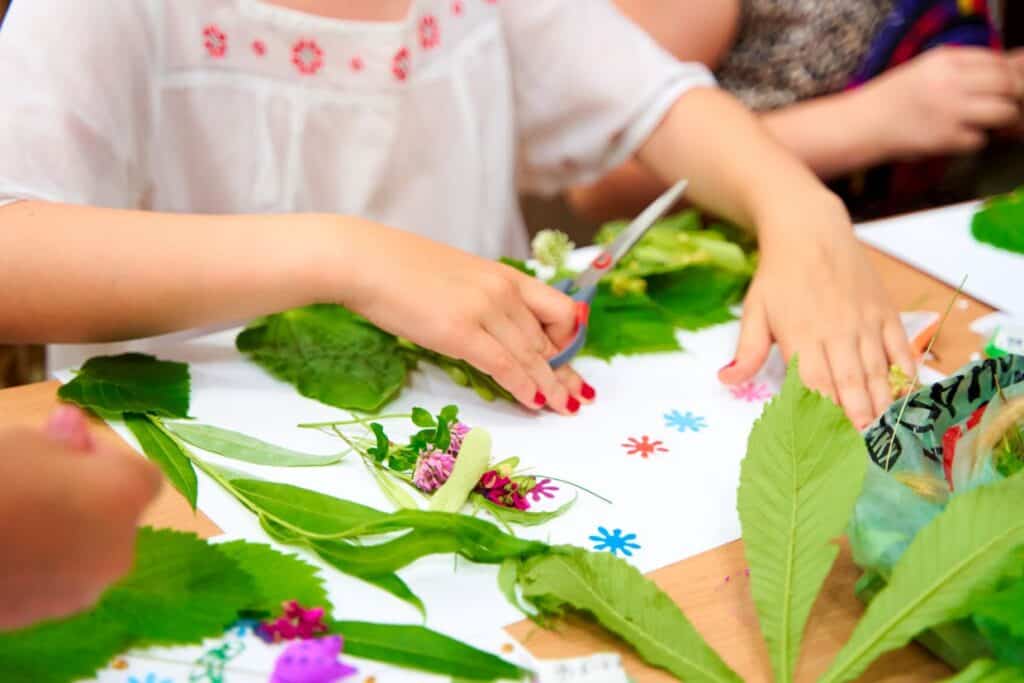 A group of children are making crafts with leaves and flowers.