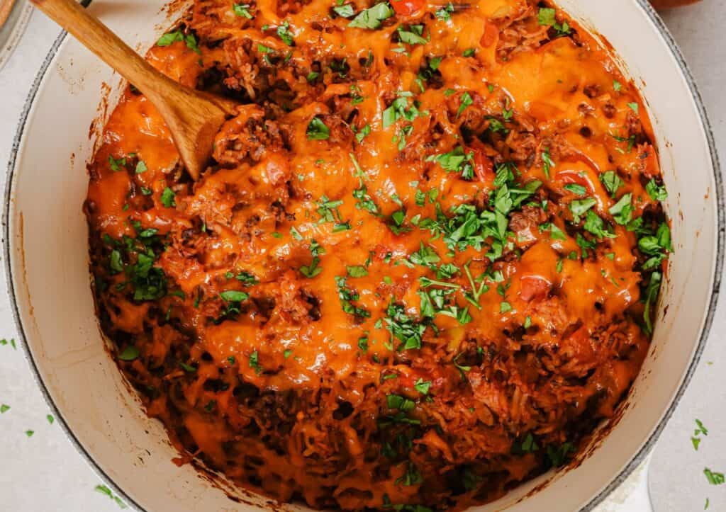 Stuffed bell pepper casserole in a pan with a wooden spoon.