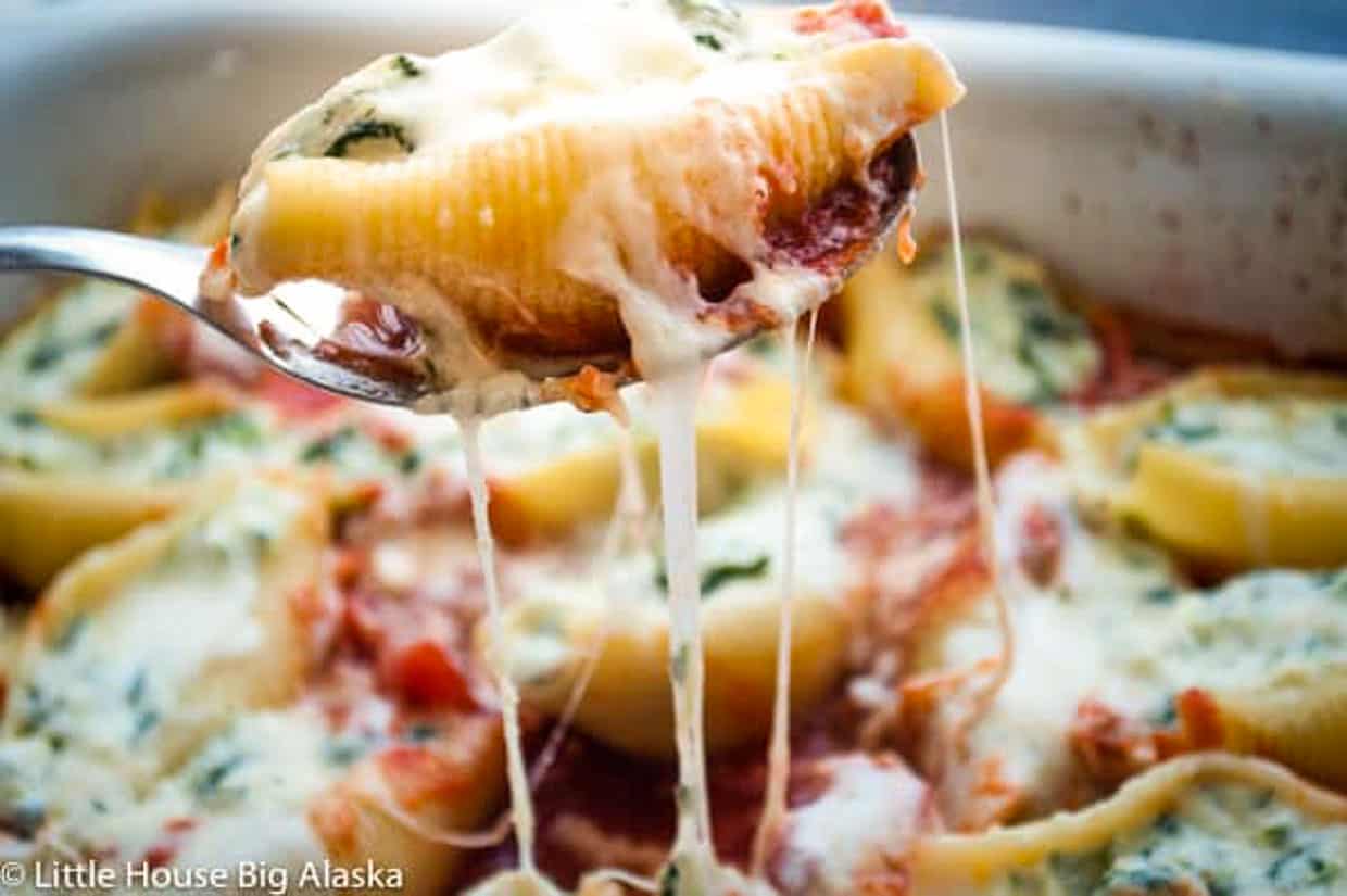 Stuffed shell in a spoon with mozzarella cheese stretching.