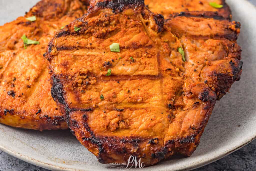 Grilled pork chops on a plate with green onions.