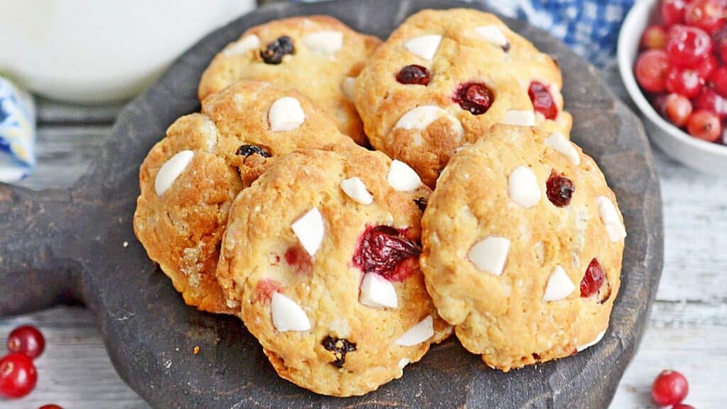 A plate of cookies with white chips and cranberries.
