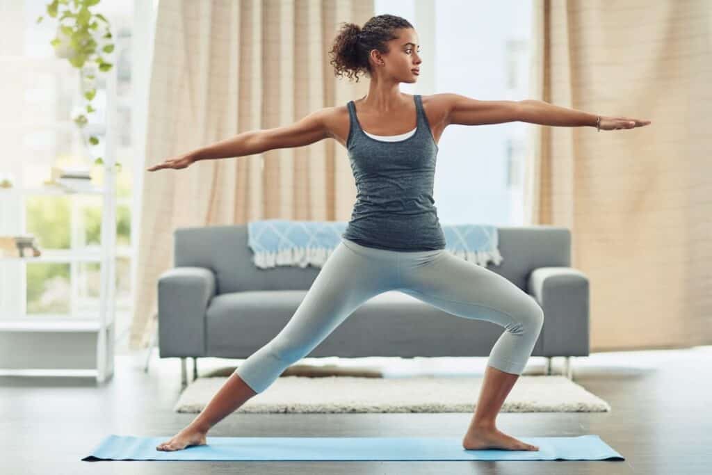 A woman practicing yoga with beginner accessories in her living room.