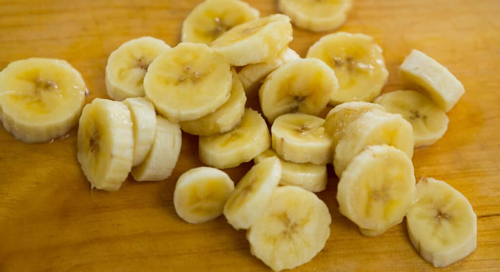 Sliced bananas on a wooden cutting board.
