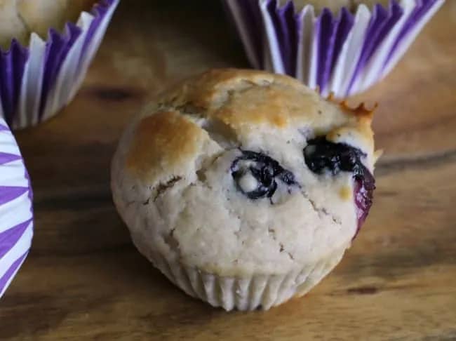 Blueberry muffin on a wooden serving board.