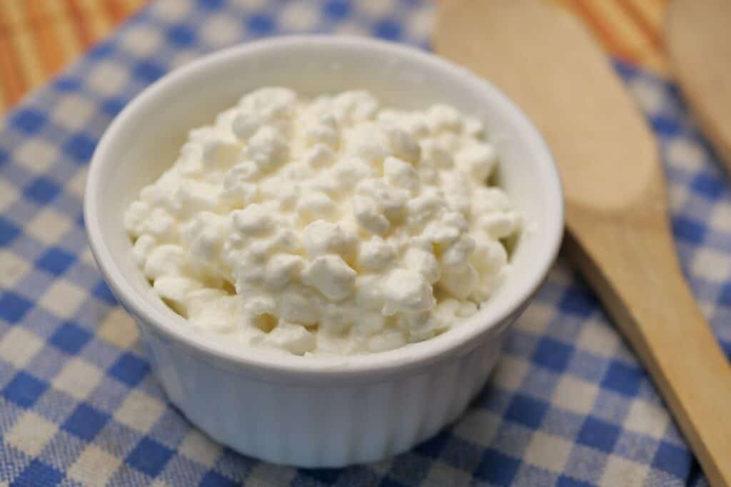 Cottage cheese in a bowl on a blue and white cloth.