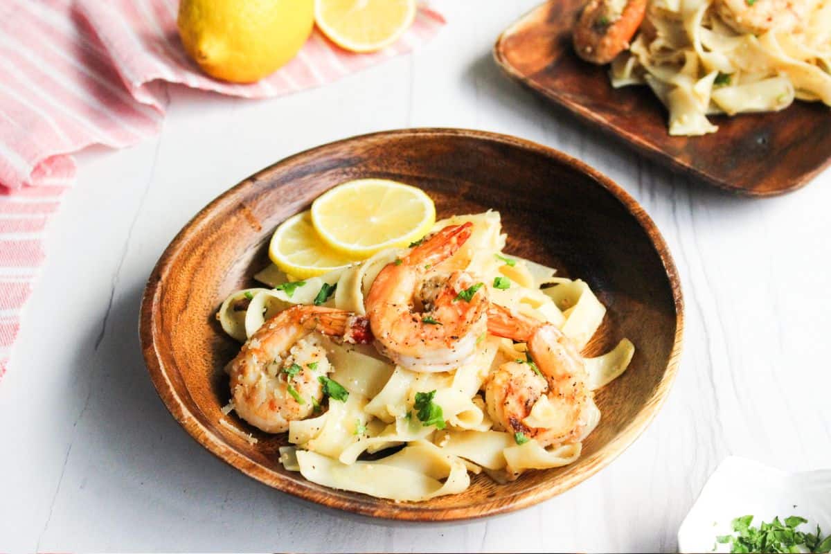 A bowl of shrimp pasta with lemon and parsley.