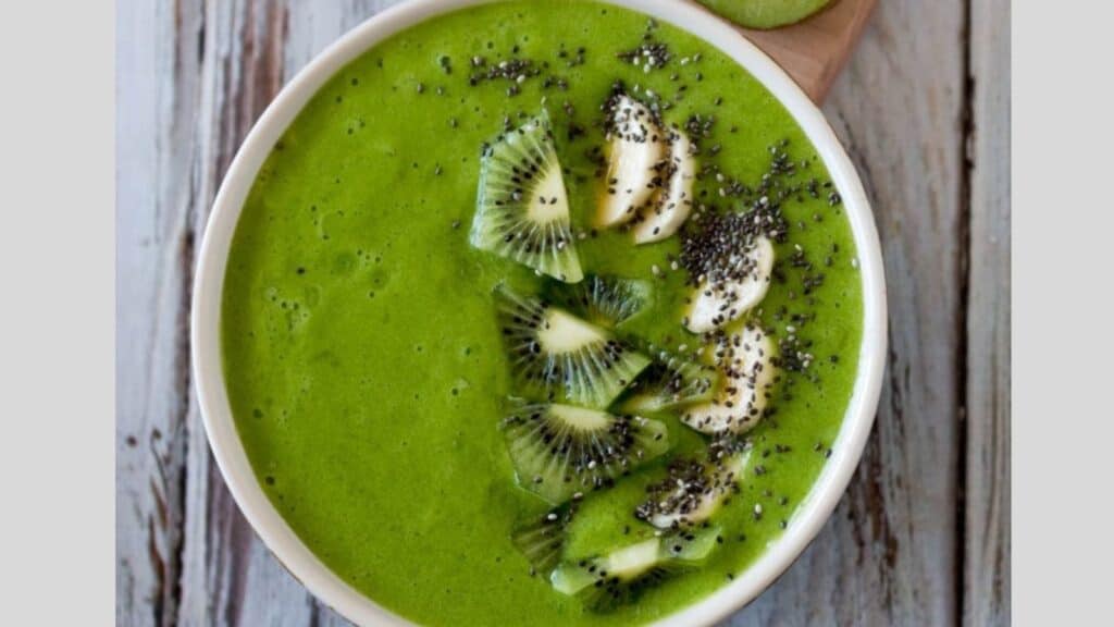 A bowl of green smoothie with kiwi and chia seeds.