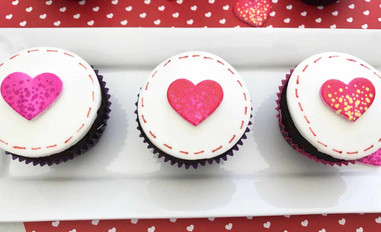 White rectangle plate with three cupcakes and Valentine's Day decor.