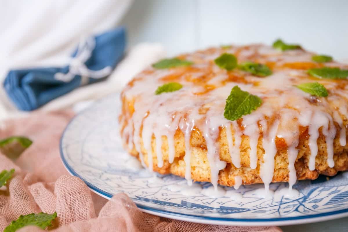 A peach pound cake with icing on a plate.