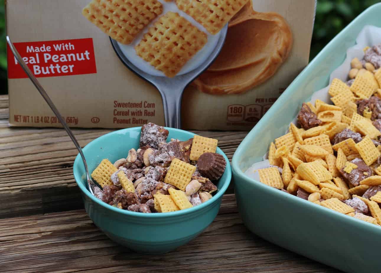 Teal bowl of chex party mix next to a cereal box and casserole dish.
